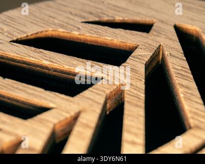 Nahaufnahme eines komplizierten Holzgitterdesigns. Natürliche Körnungen unterstreichen die Handwerkskunst. Dunkle Schatten Rahmen geometrische Ausschnitte. Warme Töne werden hervorgehoben Stockfoto