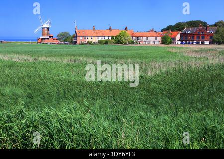 Windmühle steht an klaren Tagen in der Nähe von Häusern und grünen Feldern in Cley-next-the-Sea, Norfolk, England Stockfoto