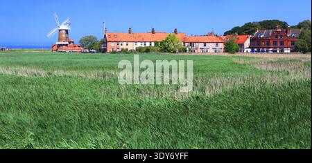 Die Windmühle in Norfolk, England, steht neben Häusern und Feldern in Küstennähe und zeigt das ländliche Leben und die Küstenlandschaft Stockfoto
