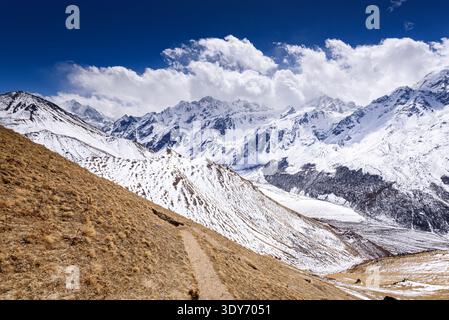 Der gewundene Bergweg führt von Kyanjin Ri mit schneebedeckten Graten und Langtang-Gipfeln in der Ferne in Nepal hinunter Stockfoto
