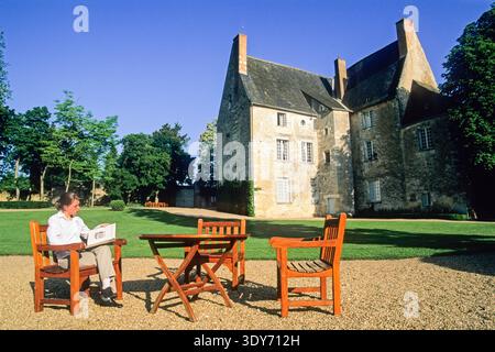Die junge Frau liest an einem sonnigen Tag im Garten des historischen Chateau de Sache in Frankreich Stockfoto