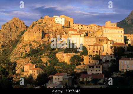 Sonnenuntergang über dem Dorf Speloncato mit Gebäuden und felsigen Hügeln in der Balagne Region Oberkorsika Stockfoto