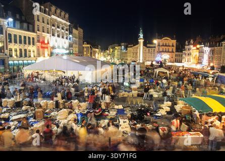 Straßenmarkt in der Nacht auf dem Grand Place in Lille während Braderie mit vielen Besuchern, die an Ständen stöbern und Artikel kaufen Stockfoto