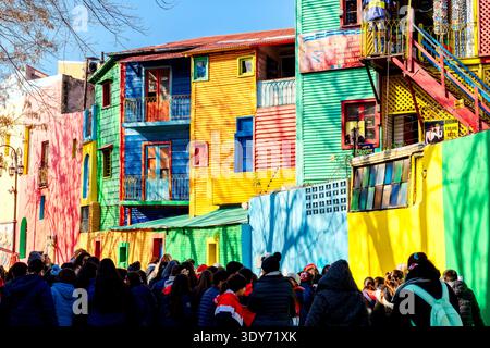 Touristen erkunden lebendige Häuser und helle Mauern in Caminito, während sie ihren Besuch in La Boca in Buenos Aires, Argentinien, genießen Stockfoto