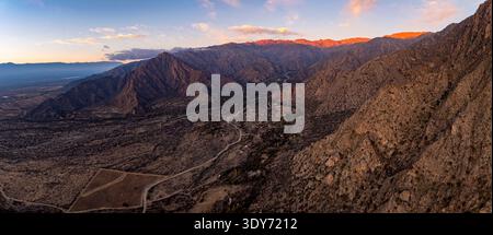 Die Straße schlängelt sich bei Sonnenuntergang durch die Berglandschaft von Cafayate im Calchaqui Valley, Provinz Salta, Argentinien Stockfoto