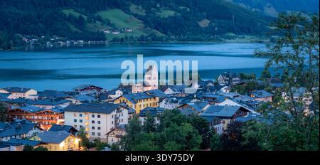 Die erhöhte Aussicht zeigt Zell am See mit dem Zeller See und Gebäuden in der Abenddämmerung in Salzburg, Österreich Stockfoto