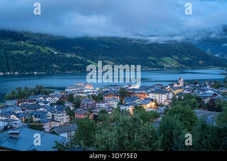 Blick auf Zell am See und den Zeller See während der Abenddämmerung in Salzburg, Österreich, mit Lichtern, die beginnen zu leuchten Stockfoto