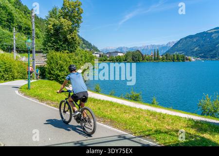 Radfahrer, der an einem sonnigen Tag in Zell am See, Salzburg, Österreich, entlang des Weges am Zeller See fährt Stockfoto