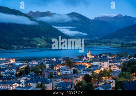 Blick auf Zell am See und Zeller See in der Abenddämmerung mit Bergen und Wolken im Hintergrund, Zell am See, Österreich Stockfoto
