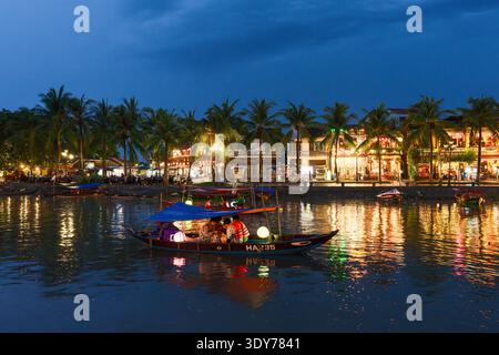 Touristenboote fahren in der Abenddämmerung auf dem Fluss Thu Bon mit Lichtern und Palmen in Hoi an, Provinz Quang Nam, Vietnam Stockfoto