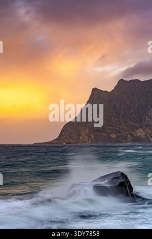 Wellen brechen bei Sonnenuntergang in Leknes auf den Lofoten in Norwegen gegen Felsen Stockfoto