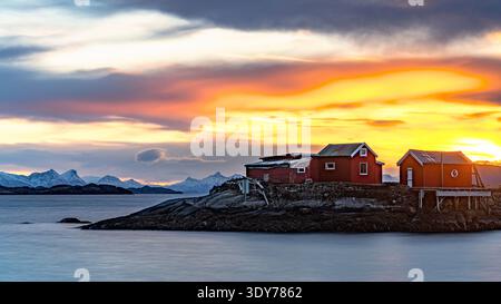 Der goldene Sonnenaufgang beleuchtet die Rrorbu-Hütten am Wasser auf den Lofoten-Inseln, Norwegen Stockfoto