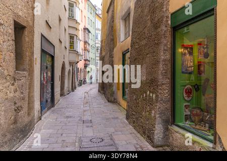 Enge Straße mit Geschäften in der Altstadt von Innsbruck an einem sonnigen Sommertag, an dem Menschen spazieren gehen und die Gegend erkunden Stockfoto