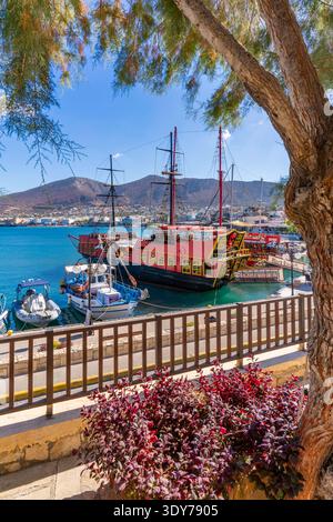 Boote legten an einem lebhaften Hafen mit klarem Wasser und Hügeln in der Ferne in Hersonissos Kreta Griechenland an Stockfoto