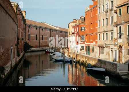Blick auf den Kanal mit Booten und farbenfrohen Gebäuden in Venedig an einem klaren Tag unter blauem Himmel in Veneto, Italien Stockfoto