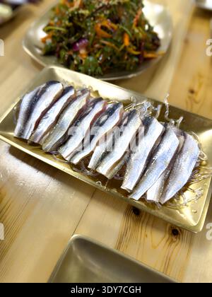 Frisches Sashimi im Gizzard-Stil, serviert mit koreanischen Beilagen auf einem Tisch, traditionellen koreanischen Meeresfrüchten und gesunder asiatischer Küche. Stockfoto