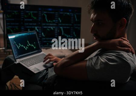 Trader analysieren Kryptowährungen und Börsendiagramme, überwachen Anlagedaten auf mehreren Bildschirmen, verwalten Finanzportfolios zu Hause, arbeiten Stockfoto