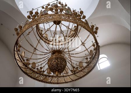 Ein niedriger Winkel eines traditionellen großen Bronzekronleuchters mit Kerzen und Ikonen in einer hellen Kirche. Begriff religiöser Architektur, Orth Stockfoto
