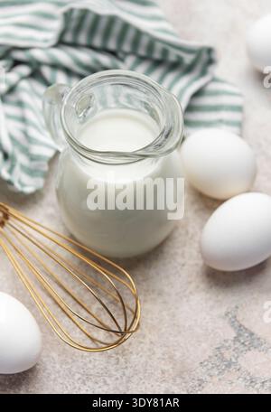 Milch, weiße Eier und ein Schneebesen zum Kochen oder Backen Stockfoto