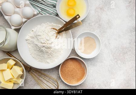 Verschiedene Schüsseln mit Mehl, Eiern, Zucker, Hefe, Butter, und Milch zum Backen Stockfoto