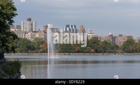 Ein Blick über das Jacqueline Kennedy Onassis Reservoir im Central Park mit dem hohen Wasserbrunnen, der aus der Mitte des Sees steigt. Stockfoto