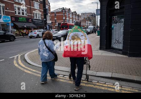 Iranische Gemeinde in Finchley, Nord-London. Einheimische gehen die Hauptstraße hinunter und tragen die iranische Flagge. Stockfoto