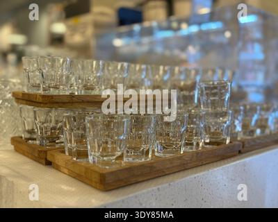 Die Glaswaren sind ordentlich auf Holztabletts angeordnet und erzeugen einen Hintergrund mit Bokeh-Füllung. Mobiles Foto Stockfoto