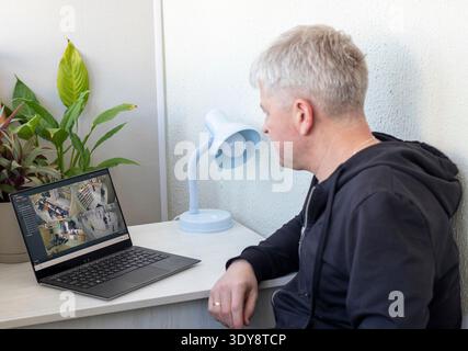 Man überwacht Aufnahmen von cctv-Kameras auf seinem Laptop Stockfoto