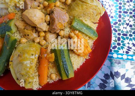 Ein farbenfroher Couscous-Teller mit Huhn, Kichererbsen und verschiedenen Gemüsesorten einschließlich Karotten, Zucchini und Kohl Stockfoto