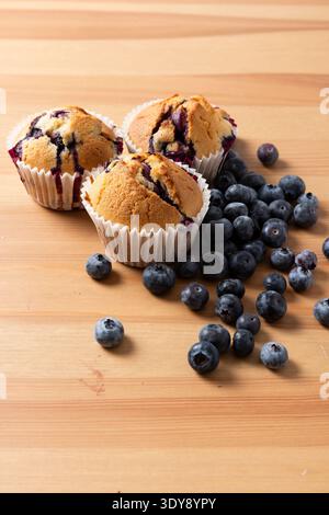 Drei hausgemachte Blueberry Muffins mit verstreuten frischen Blaubeeren auf Holztisch, vertikal Stockfoto