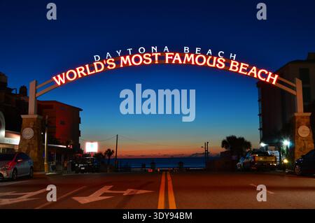 Bei Sonnenaufgang erstreckt sich ein größeres beleuchtetes Schild auf der anderen Straßenseite und begrüßt Gäste am selbst ernannten weltberühmtesten Strand von Daytona Beach. Stockfoto
