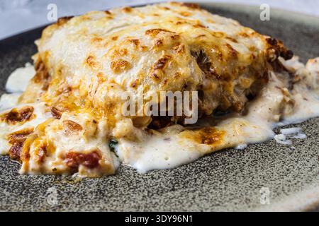 Lasagne mit geschmolzenem Käse, serviert in einer braunen Steingut-Schale. Typisch italienische und mediterrane Küche Stockfoto