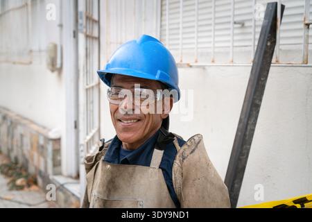 Bauarbeiter tragen Schutzausrüstung, während er die Kamera anlächelt Stockfoto