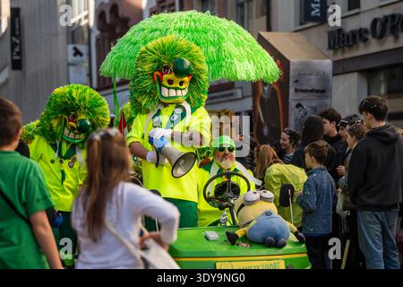 Basel, Schweiz – 25. März 2026: Basel, Schweiz – 25. März 2026: Hellgrüne Karnevalsfiguren interagieren mit Zuschauern aus einer dekorierten Stadt Stockfoto