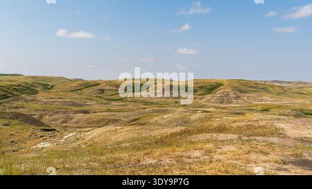 Erodierte Schichten bilden Badlands, wenn sie sich vom Prärieboden heben. Ihre Texturen und Farben stehen im Grasslands National Park vor einem tiefblauen Himmel. Stockfoto