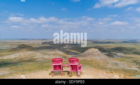 Fir Mountain, SK CANADA - 6. August 2024: Die legendären roten Stühle des Parks in Kanada mit Blick auf Prärie-Badlands im Grasslands-Nationalpark. Stockfoto