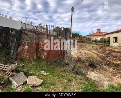 Portugal, Rehabilitation - 6. März 2026: Verlassenes rostiges Metalltor und Betonmauer in einem vernachlässigten Anwesen warten auf die Sanierung der Ruine Stockfoto