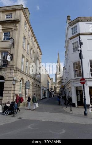 Blick auf eine Straße im historischen Zentrum von Bath, Somerset, England, Großbritannien, mit Fußgängern und Turm der St. Michael's Church in der Ferne Stockfoto