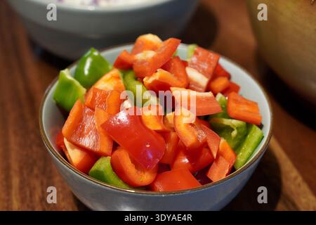 Grün-rot geschnittene Paprika in einer Schüssel auf hölzerner Arbeitsplatte Stockfoto