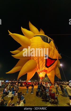Während des Miami Hot Air Balloon Festivals leuchtet im Tamiami Park ein riesiger gelber, sonnenförmiger Heißluftballon mit schwarzer Sonnenbrille und einem lächelnden Gesicht. Stockfoto