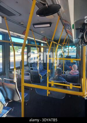 Toronto, ON, Kanada - 5. August 2025: Das Bild zeigt das Innere eines öffentlichen Busses mit gelben Handläufen und sitzenden Passagieren. Stockfoto