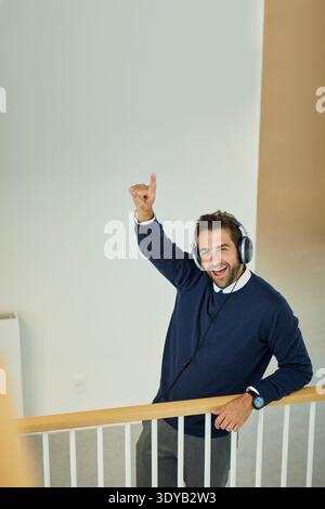 Oben, Porträt und Mann im Büro, Kopfhörer und Musik hören, feiern und Investor. Finanzberater, Sänger oder Person am Arbeitsplatz Stockfoto