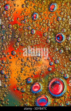 Dichtes Feld aus goldenen und orangen Öltropfen auf einem dunklen strukturierten Hintergrund, wodurch eine reichhaltige organische Oberfläche mit mikroskopischen Details entsteht. Stockfoto