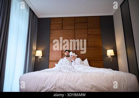 Paare, die sich im Hotelzimmer entspannen und in Bademänteln lächeln Stockfoto