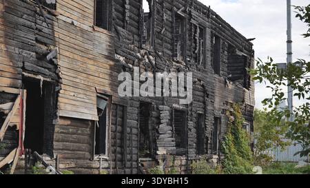 Verbranntes Haus in Zerstörung, verbranntes Holz und Baumstämme zeigen Brandschäden Stockfoto