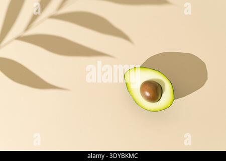 Avocado mit tropischen Palmen hinterlässt Schatten auf pastellgrünem Hintergrund. Natur-Food-Layout. Sommerfrucht-Konzept. Flache Lagen. Stockfoto