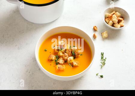 Köstliche Kürbissuppe, garniert mit Croutons und Thymian auf hellem Hintergrund. Stockfoto
