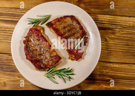 Gegrillte Schweinefleisch-Steaks mit Rosmarin auf Holztisch. Draufsicht Stockfoto
