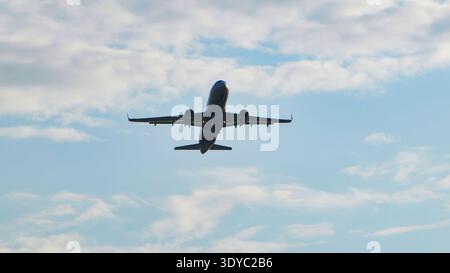 Kommerzielles Passagierflugzeug startet und steigt in einen blauen bewölkten Himmel, Tiefwinkelansicht. Stockfoto