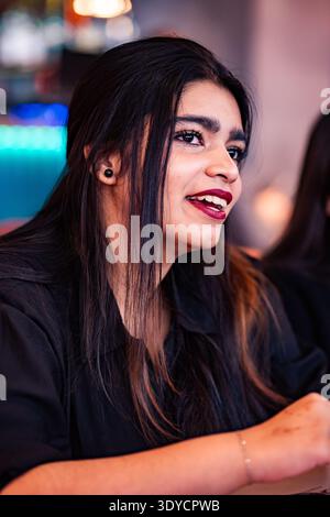 Junge indianerin lacht, lächelt mit roten Lippen und dunklen Haaren Stockfoto